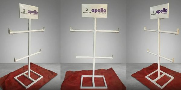 White metal Apollo Tyres stand for two-wheeler display on red cloth.