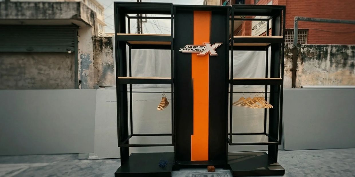 Modern Harley Davidson clothing rack with hangers in an outdoor setting.