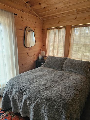 Cozy wooden bedroom with a textured gray bedspread and soft natural light.