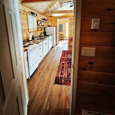 Rustic wooden kitchen with white appliances and a colorful rug.