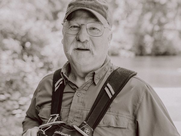 Older man in outdoor gear smiling at the camera.
