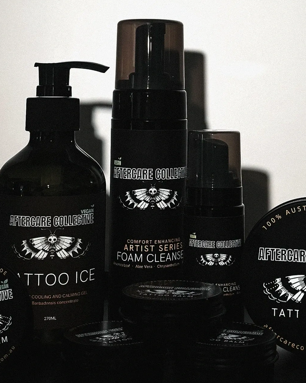 Black tattoo aftercare products with white labels and moth logo.