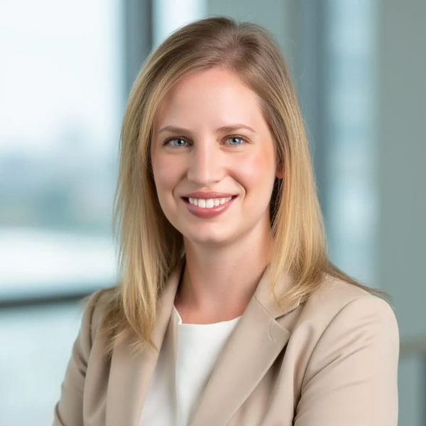 Professional woman in beige blazer smiling confidently indoors.