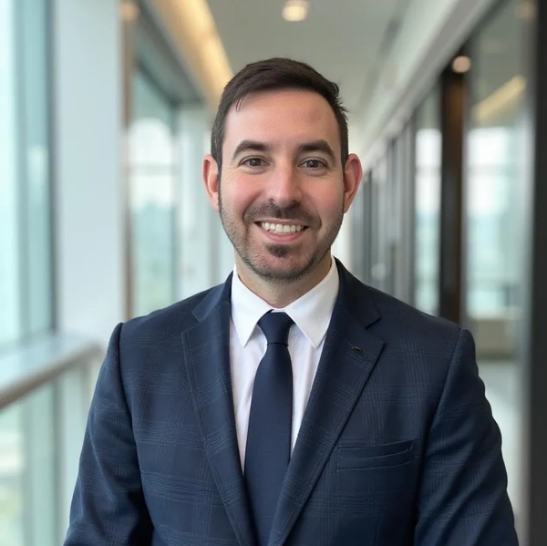Man in a suit smiling confidently indoors.