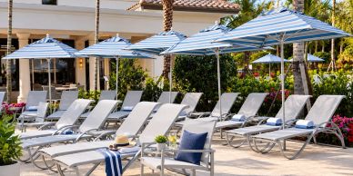 Row of lounge chairs with umbrellas by a poolside.