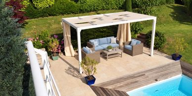 Cozy outdoor seating area by a pool under a pergola.