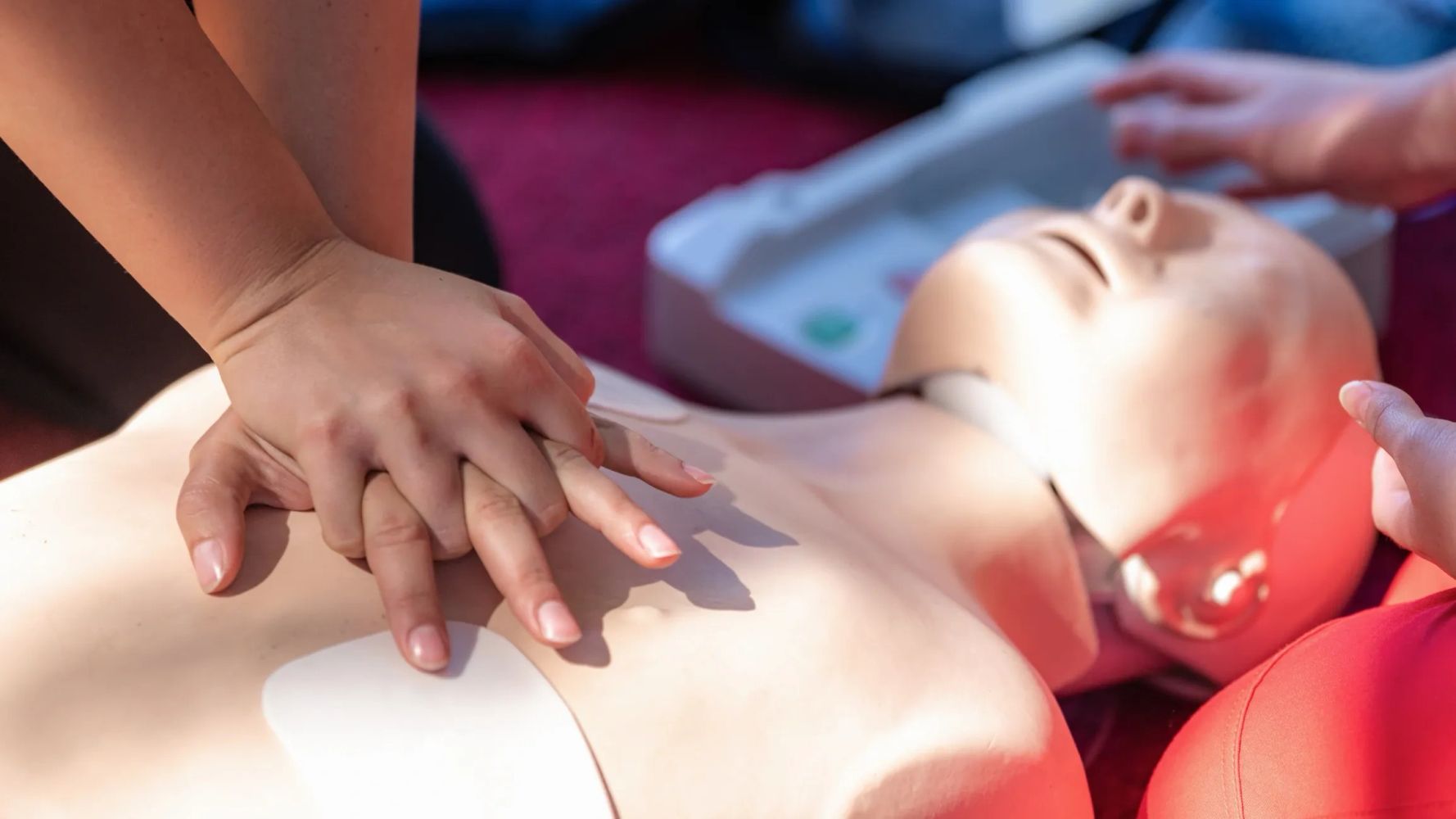 Hands performing CPR on a medical training mannequin.