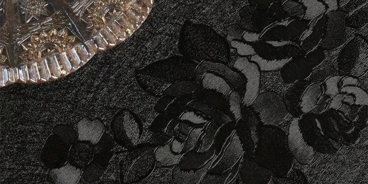 Close-up of dark floral fabric with a decorative silver plate corner.