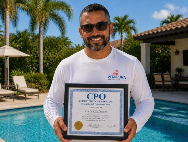 Man proudly holds Certified Pool Operator certificate by a poolside.
