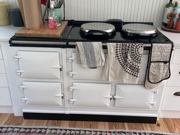 Classic white kitchen stove with towels hanging and utensils on the side.