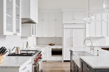 Bright modern kitchen with white cabinets and marble countertops.