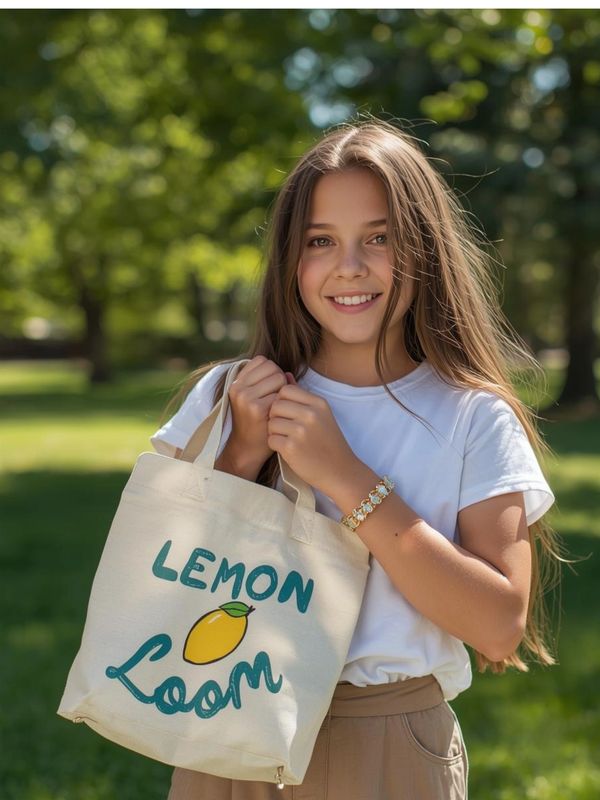Smiling girl holding a tote bag with 'Lemon Loom' print in a sunny park.