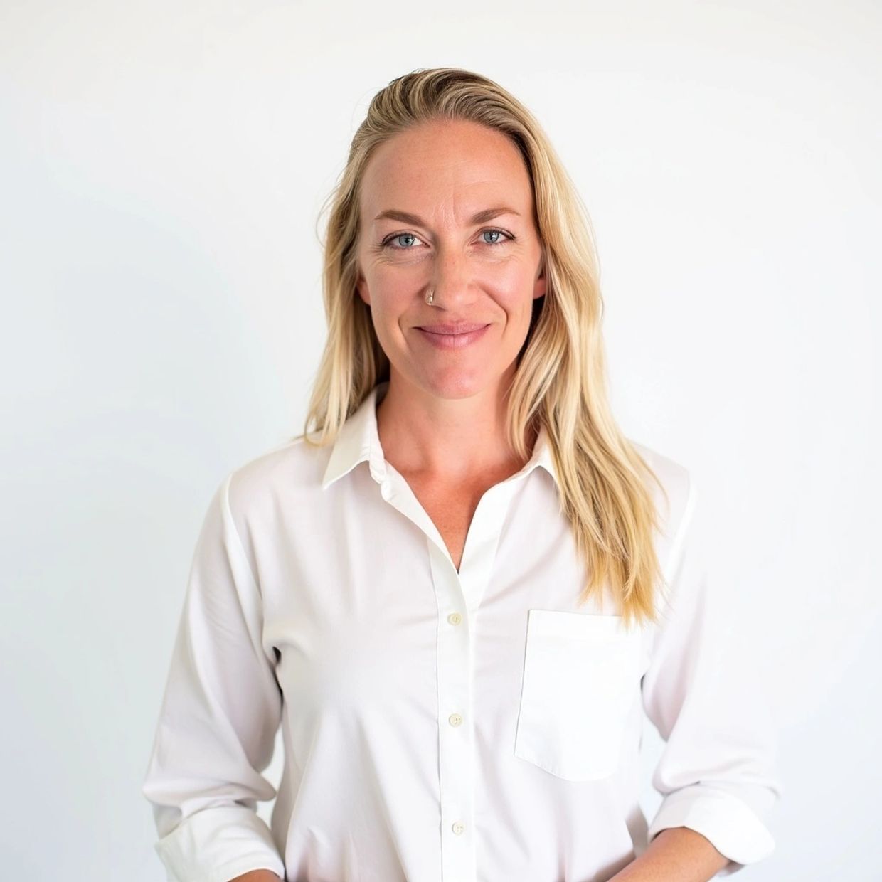Smiling woman in white shirt posing against a plain background.