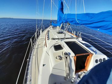 View of the deck of Courageous, a 37-foot Hunter sailboat, under full sail on Charlotte Harbor