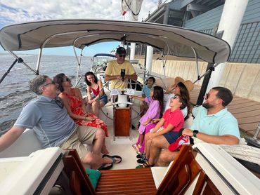 Group of six guests in the cockpit of Courageous sailboat while Captain Curtis gives orientation.