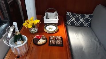 Interior cabin of the Courageous sailboat with champagne, chocolates, and flowers set up for a roman