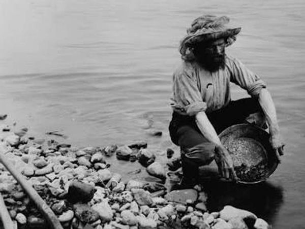 Man panning for gold in a river.