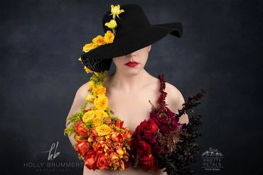 Woman wearing a floral bra and a black hat adorned with yellow flowers.