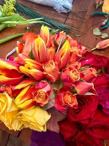 Colorful bouquet of roses and tulips being arranged by hand.