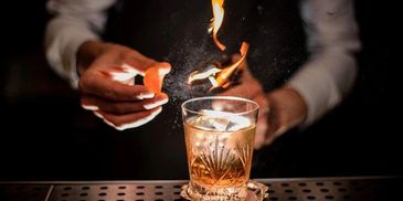 Bartender lighting a cocktail garnish on fire for presentation.