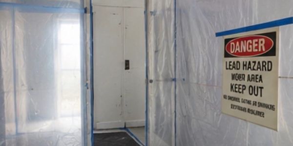 Plastic sheeting encloses a lead hazard work area with a warning sign.