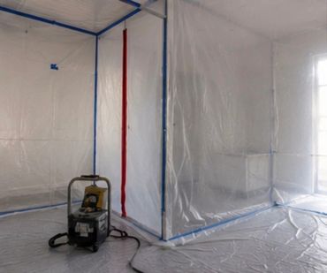 A room sealed with plastic sheeting and a dehumidifier inside.