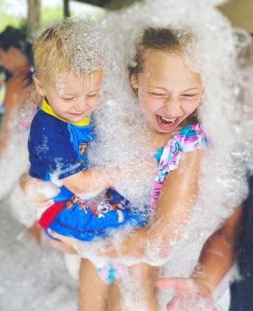 Brother and sister laughing and enjoying playing in the foam