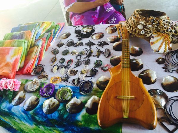 Handcrafted Hawaiian jewelry and a ukulele displayed on a colorful table.