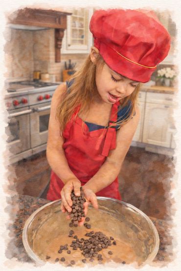 A young girl in a red chef hat and apron adds chocolate chips to a mixing bowl.