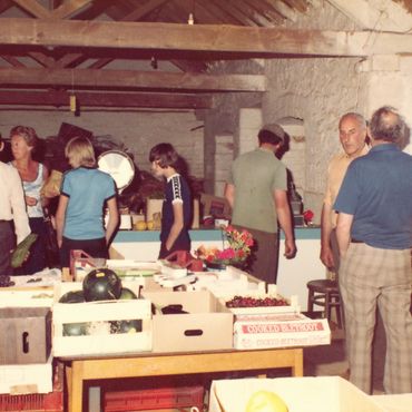 People shopping at an indoor market with wooden crates of produce.