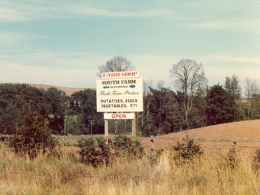 Farm shop sign advertising fresh produce like potatoes and eggs.
