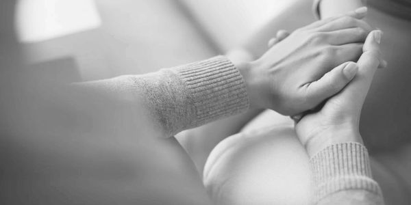 Two people holding hands in a comforting gesture.