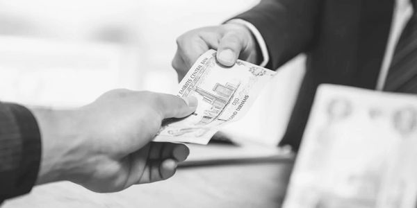 Two hands exchanging a currency note in a business setting.