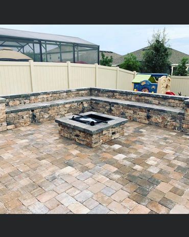 Outdoor stone fire pit with built-in seating in a backyard patio.
