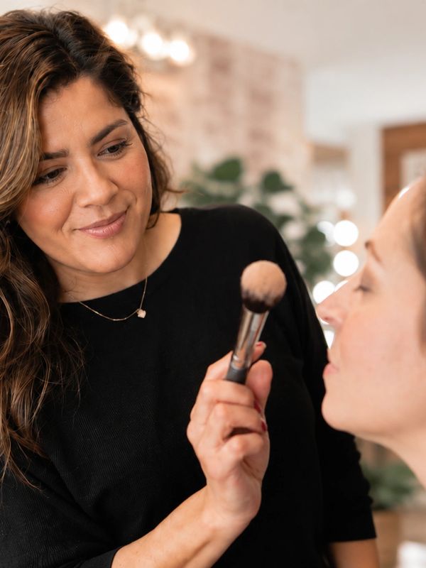 A makeup artist applying powder with a brush on a client's face.