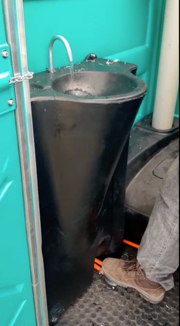 Foot pedal-operated sink inside a portable toilet.