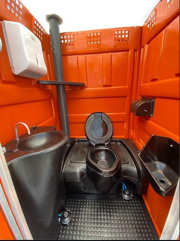 Interior of a compact orange portable toilet with black fixtures.