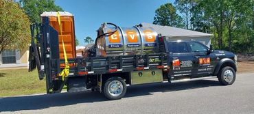 A truck equipped with portable restrooms and rental services on a residential street.