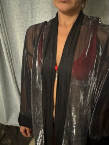 Person wearing a sheer black shiny top over a red bra.