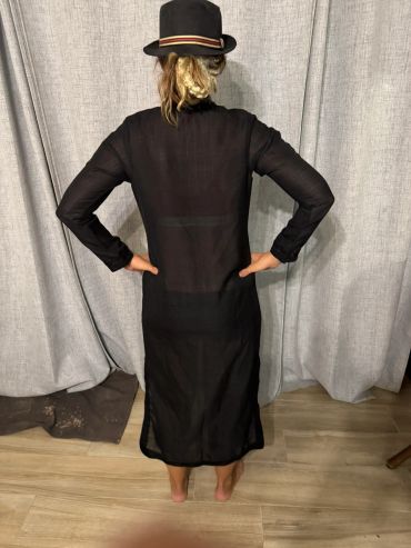 Person in black dress and hat, back facing camera.