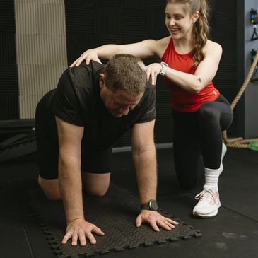 Personal Trainer assiting their client with a shoulder blade activation exercise.