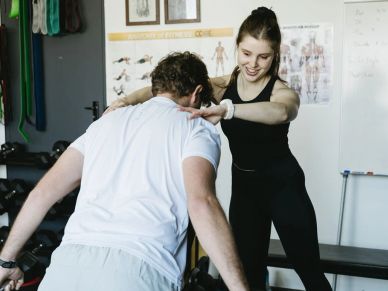Woman coaching man in exercise at gym.