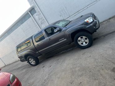 Gray Toyota Tacoma pickup truck parked by a concrete wall.