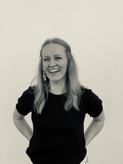 Smiling woman with musical note earrings in black shirt.