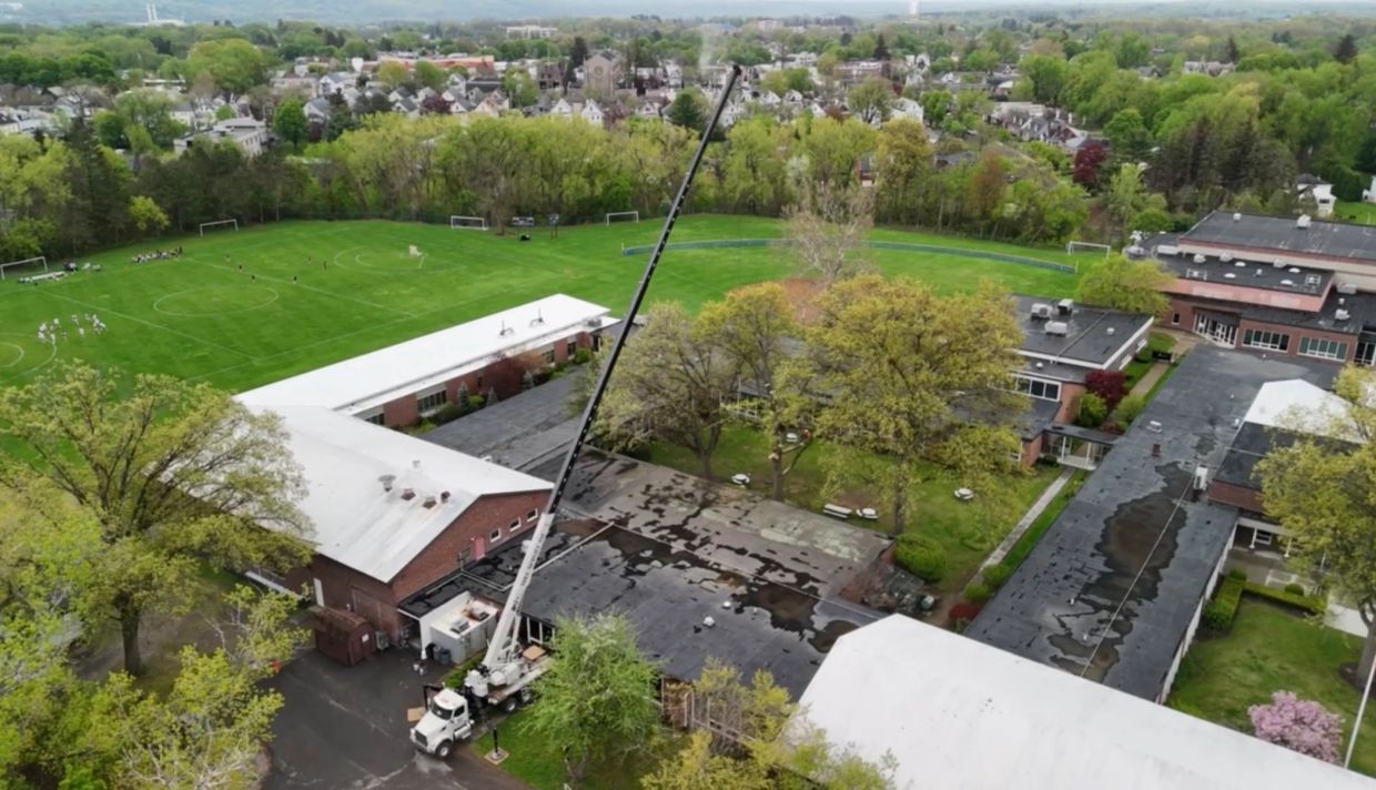 Aerial view of a school with sports fields and a crane.