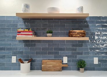 Kitchen backsplash with blue subway tile and open shelves.