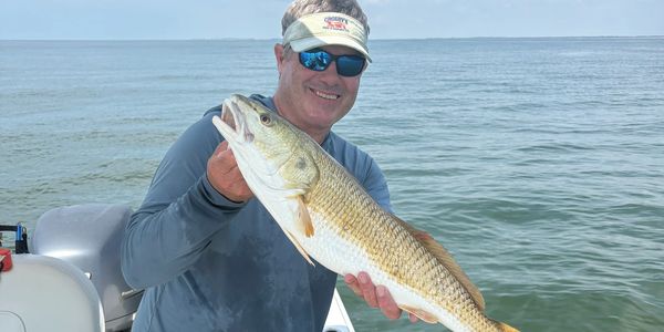 Man holding a large fish on a boat.