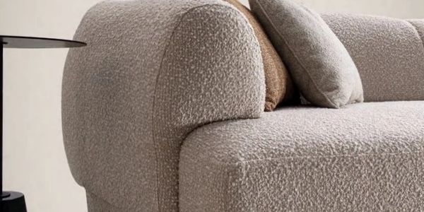 Close-up of a textured beige sofa with cushions and a side table.