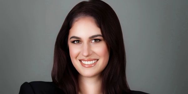 Smiling woman with dark hair against gray background.
