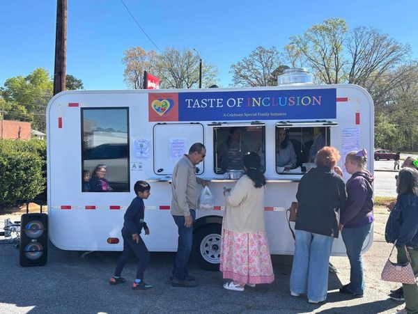 People gather at the Taste of Inclusion food truck on a sunny day.